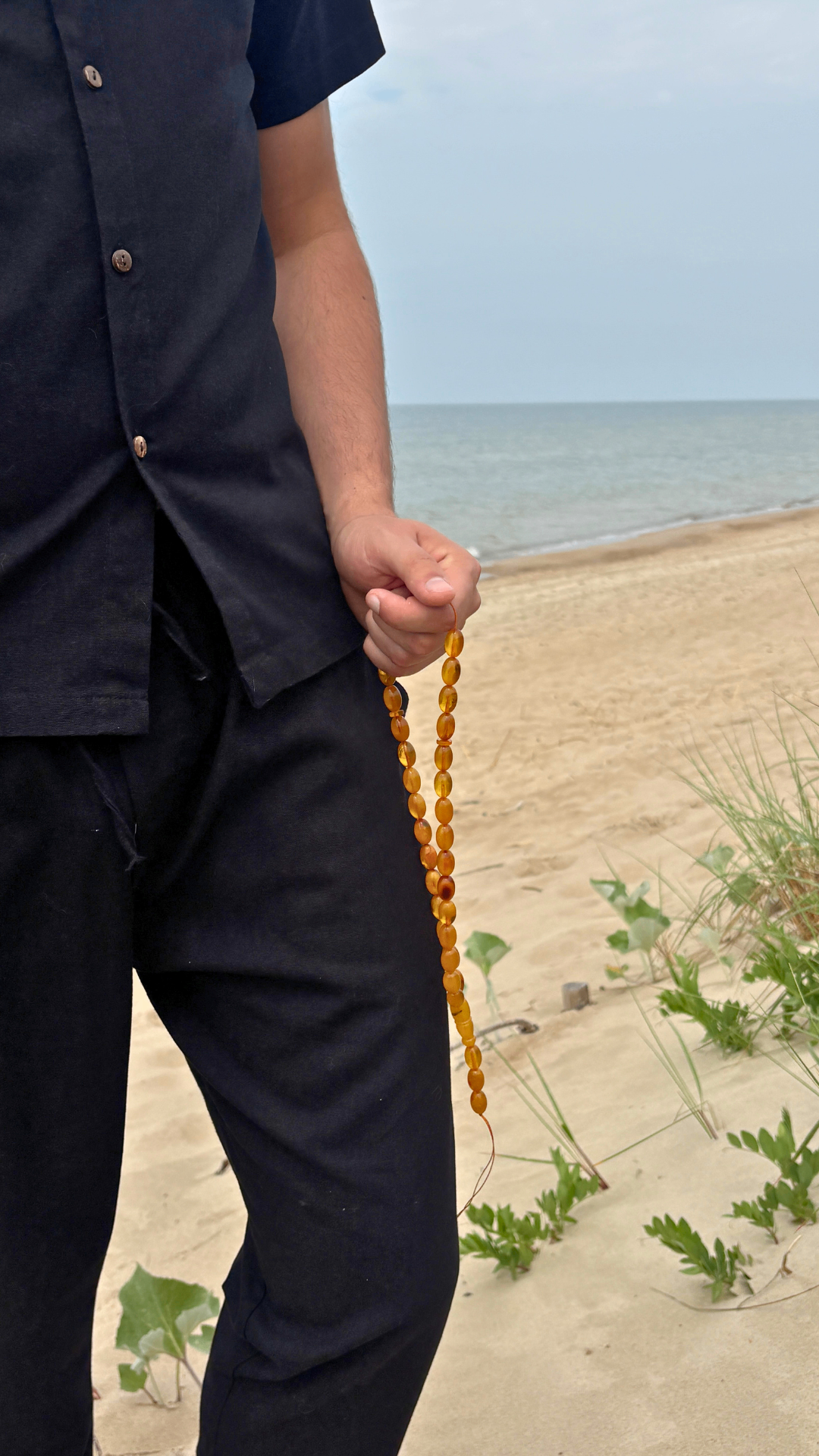 Amber tasbih carried along the Baltic shore at dawn